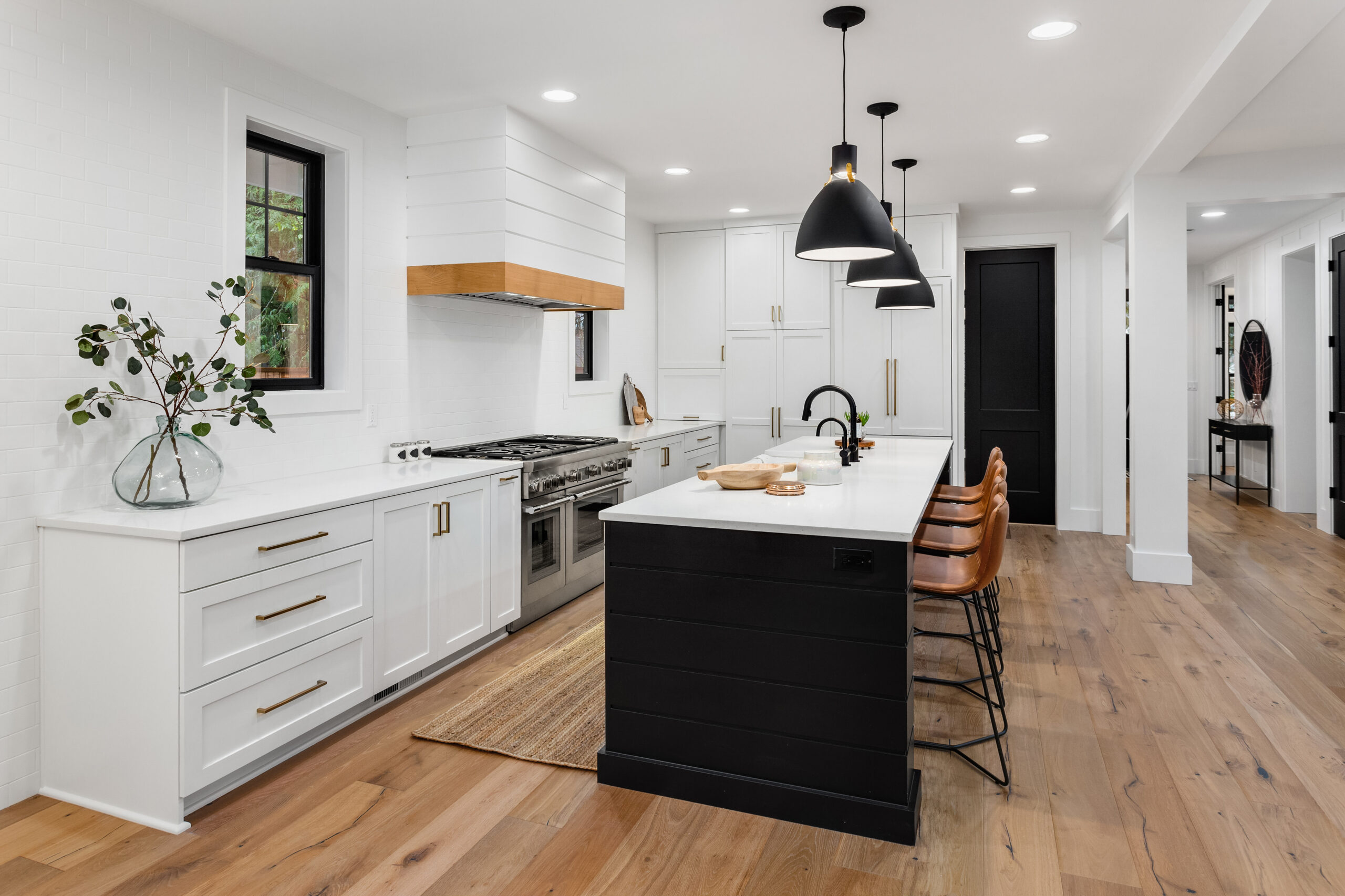 Beautiful white kitchen with dark accents in new modern farmhouse style luxury home