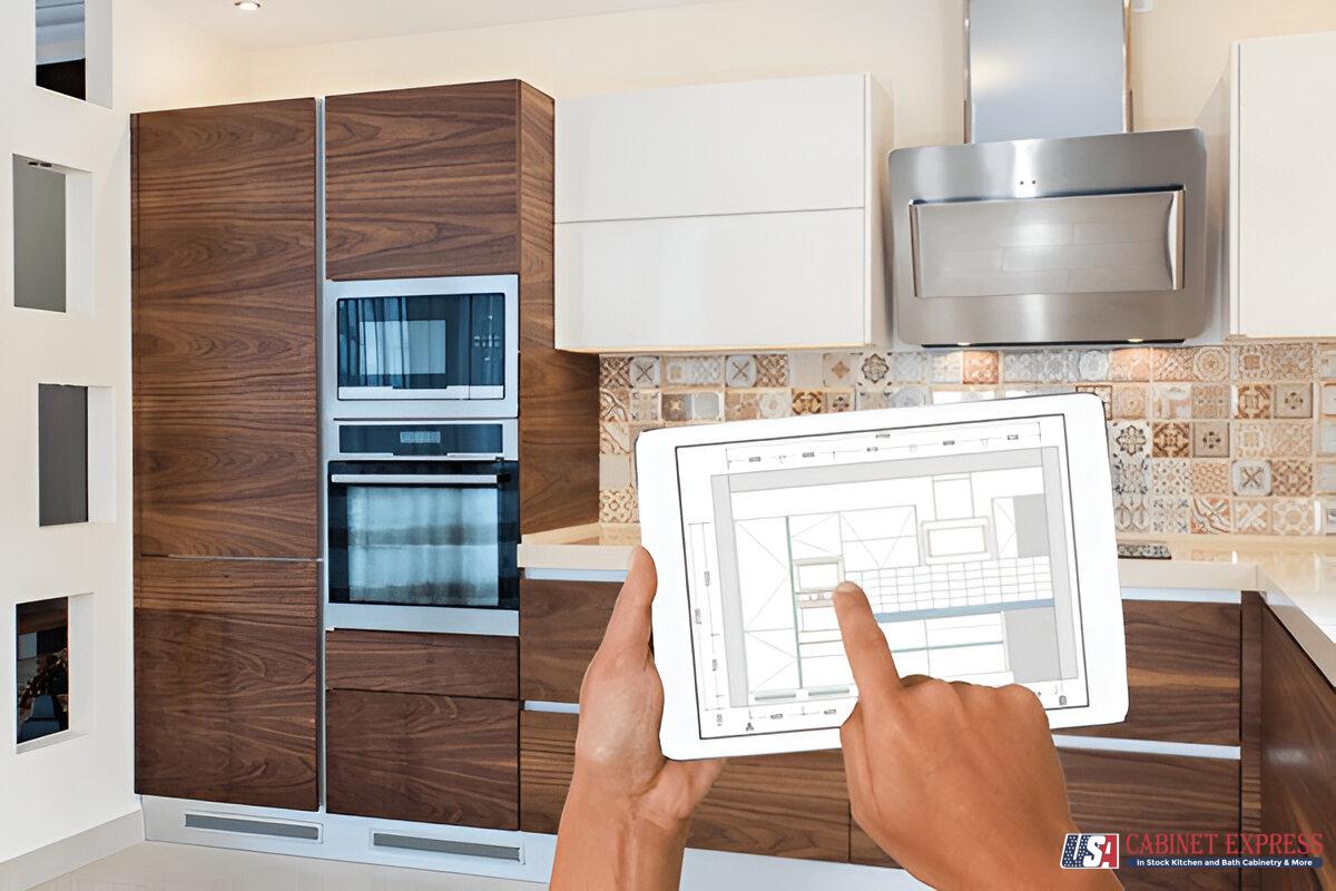 A modern kitchen with wood and white cabinetry, a patterned tile backsplash, and stainless steel appliances. A person is holding a tablet displaying a kitchen design plan. The USA Cabinet Express logo is visible in the bottom right corner.