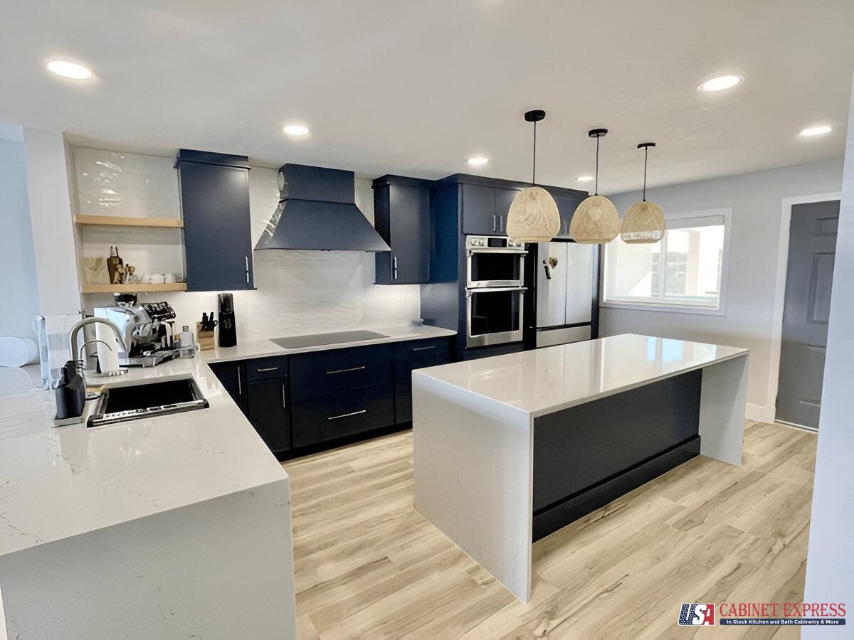 Stylish kitchen design featuring dark navy-blue cabinets, a white quartz countertop island, wooden pendant lighting, stainless steel appliances, and light wood flooring for a modern and cozy ambiance.