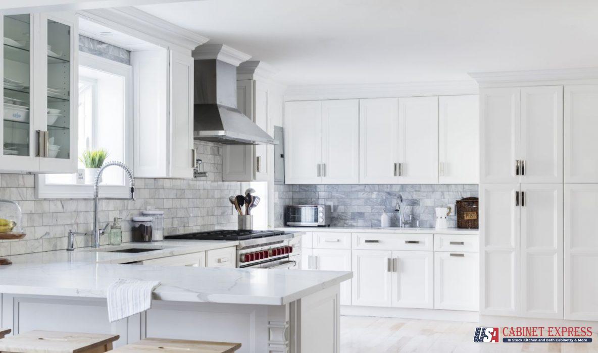 a kitchen with white cabinets and marble counter tops