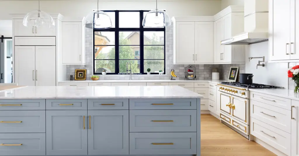Modern kitchen with a large blue island, white cabinetry, and expansive windows.