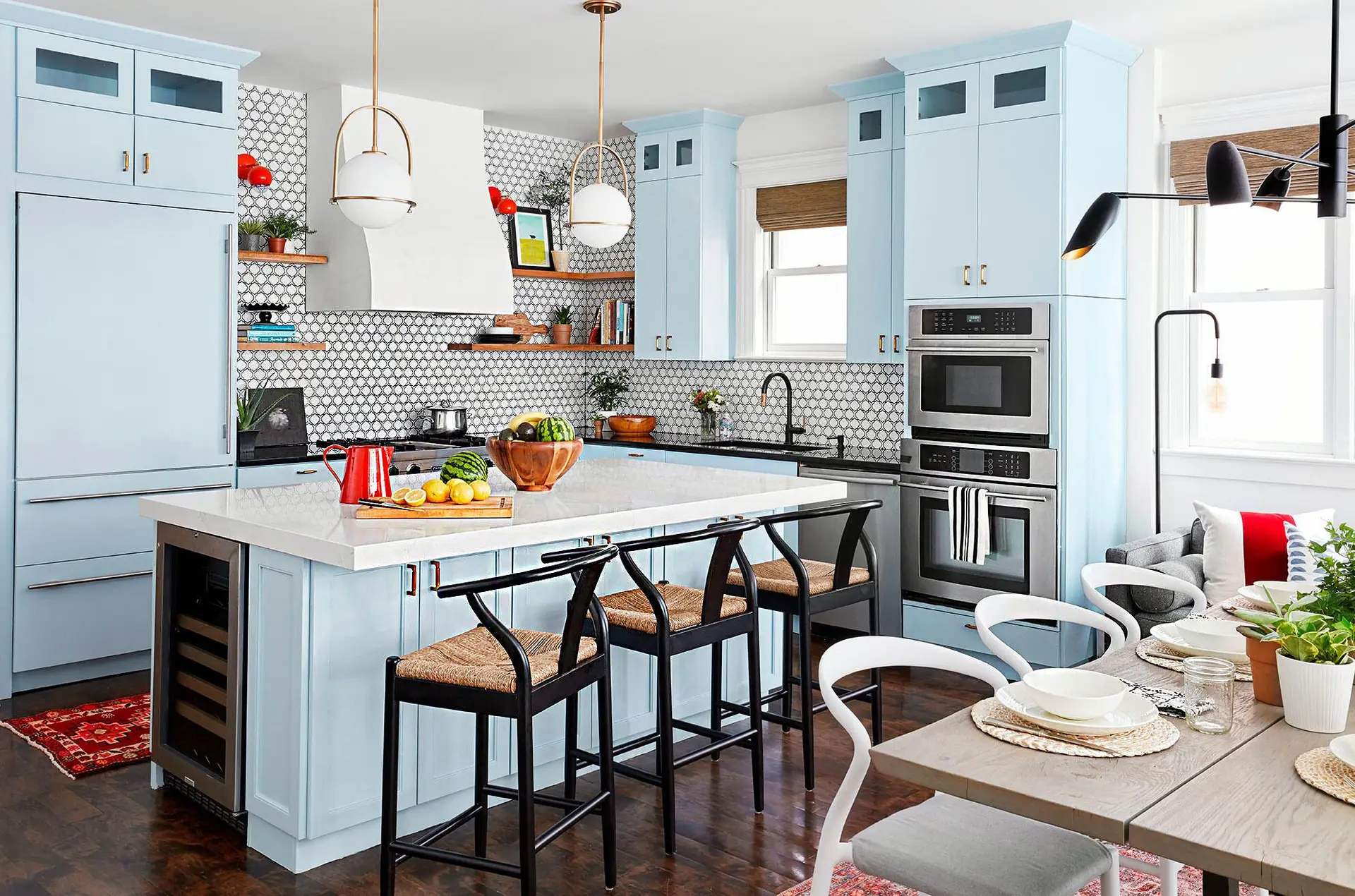 Drawer vs. Door Cabinets: Which Kitchen Storage Style Works Best? 1 A modern kitchen with light blue cabinetry, a large white island, black and woven barstools, and a stylish dining area.