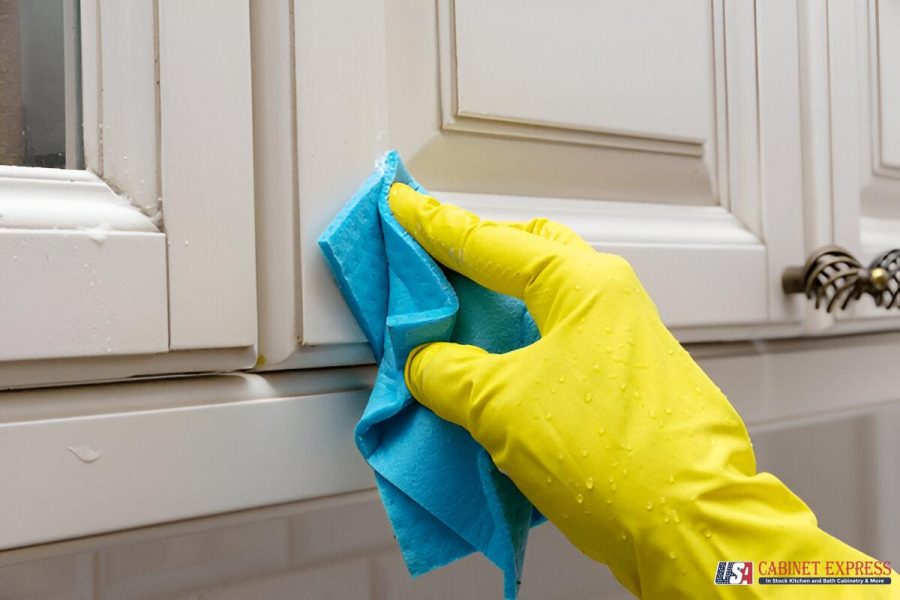 a hand in yellow glove wiping a cabinet